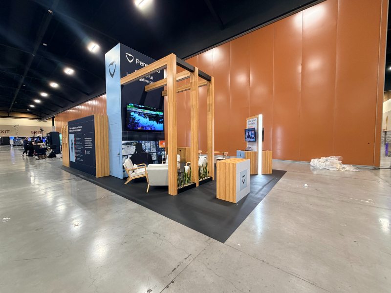 Side view of the Peregrine booth at NRTCCA 2026 showing the tower, pergola, and lounge