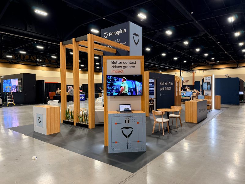 Peregrine's reconfigured modular booth at NRTCCA 2026 in Phoenix, with the wood pergola, demo counter, and lounge seating